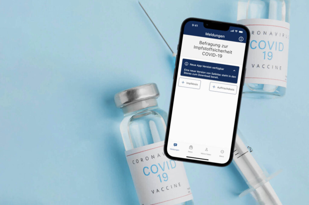 Auf einem Tisch liegen Impfstoffe und ein Handy mit der SafeVac App
