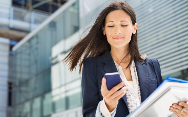 Frau mit Smartphone und Unterlagen in der Hand