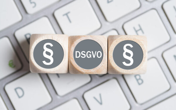 Gesetzeszeichen und DSGVO liegen in Form von Würfeln auf einer Tastatur