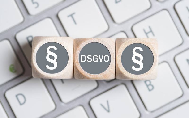 Gesetzeszeichen und DSGVO liegen in Form von Würfeln auf einer Tastatur