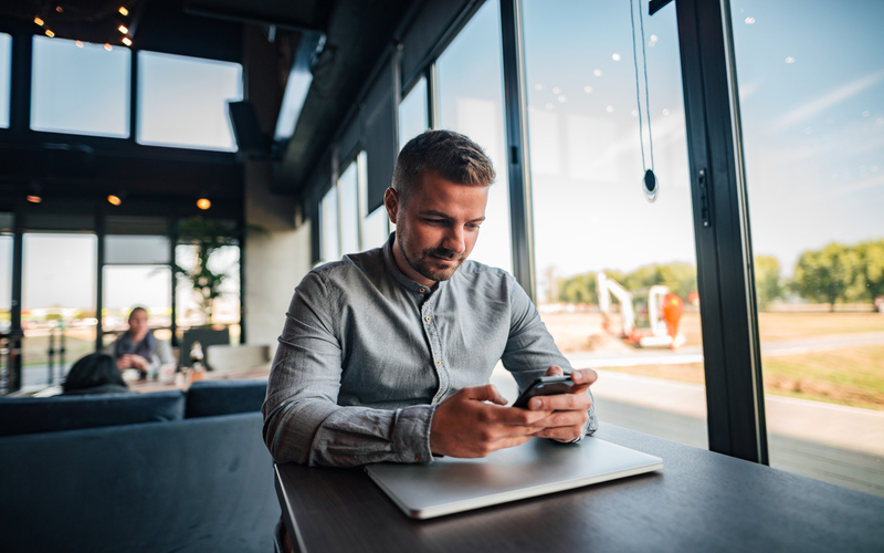 Man is at work and holds a cell phone in his hand