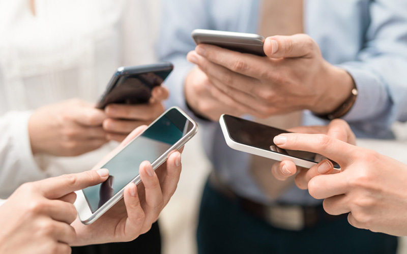 4 Personen halten ihre Smartphone in die Mitte