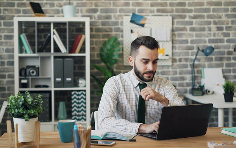 Mann sitzt am Laptop und arbeitet