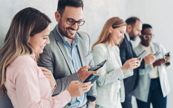 Personen stehen nebeneinander und schauen auf ihr Smartphone