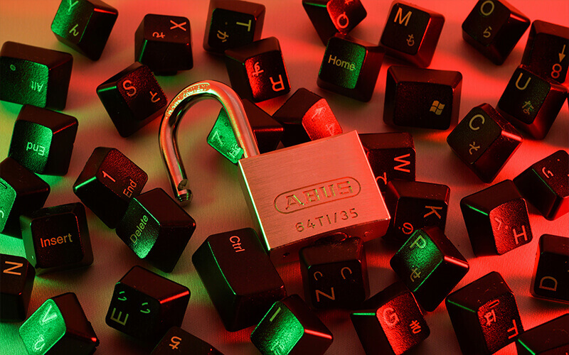 An open lock lies on individual letters of a keyboard