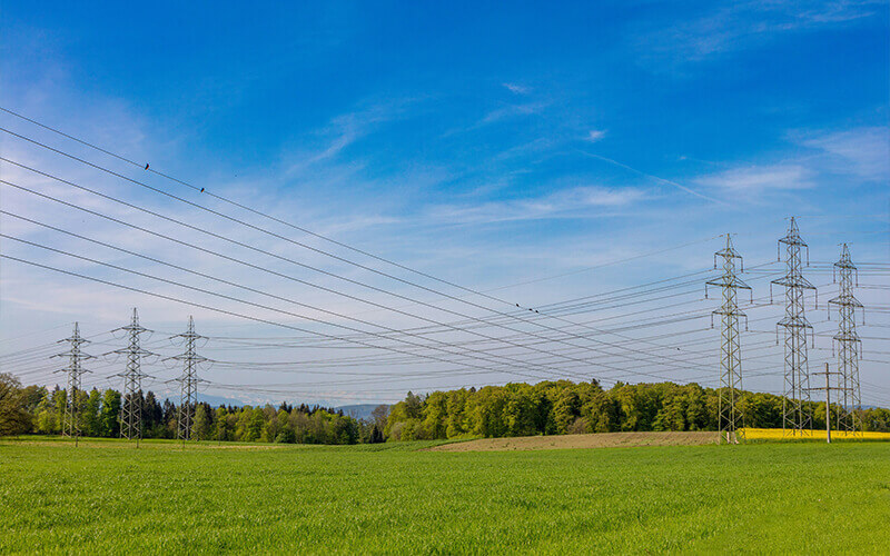 High-voltage pylons with power lines on a large meadow